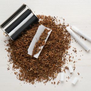 Máquina de liar y entubar con tabaco alrededor y cigarrillos preparados.