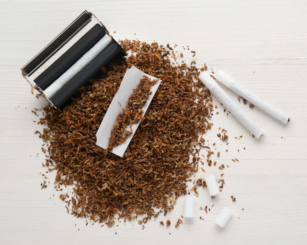 Máquina de liar y entubar con tabaco alrededor y cigarrillos preparados.